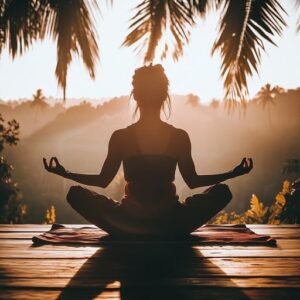 YOGA PRACTITIONER IN TREE POSE ATOP A MOUNTAIN AT SUNRISE